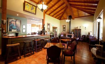 a room with wooden tables and chairs , a fireplace , and a chandelier hanging from the ceiling at Wild Cattle Creek Estate