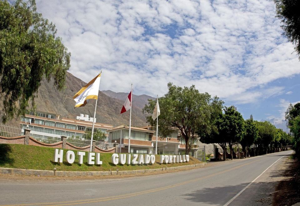 "a hotel building with a sign that says "" hotel guizaro antigua "" and several flags on the side" at Guizado Portillo Hacienda & Resort
