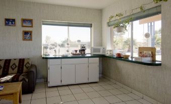 a kitchen with white cabinets , a window , and various appliances such as a microwave and coffee maker at Americas Best Value Inn Eloy/Casa Grande