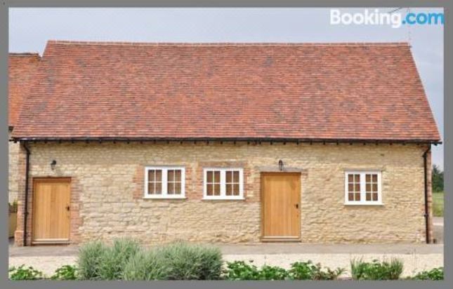 a hotel room with a large bed , a bathroom with a bathtub , and a balcony at Court Farm Barns