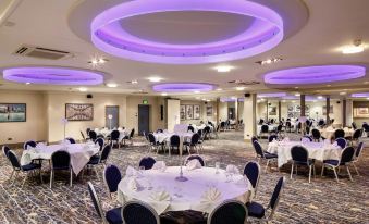 a large banquet hall with round tables and chairs set up for a formal event , possibly a wedding reception at Mercure Hull Grange Park Hotel