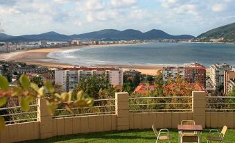 a balcony overlooking a beautiful beach and ocean , with a table and chairs set up for outdoor dining at Hotel Miramar Laredo