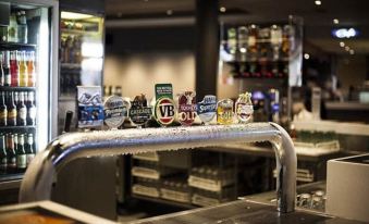 a row of beer taps in a bar , with various beers displayed on the counter at Quality Hotel Rules Club Wagga