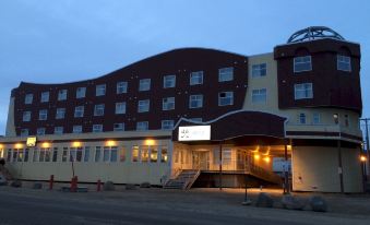 a large building with a red and white facade is lit up at night , next to a street at Hotel Arctic