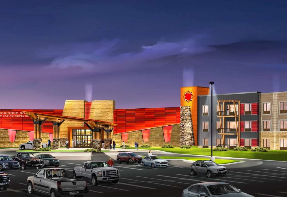 a large building with a red and gold facade is surrounded by cars on the street at Shoshone Rose Casino & Hotel