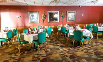 a restaurant with tables and chairs , a red wall , and framed pictures on the walls at Wrangler Inn Mobridge