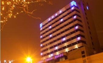 a large , modern building with blue and purple lights is illuminated by street lights at night at Grand Hotel