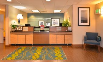 a hotel lobby with a check - in desk and a large rug on the floor , creating a welcoming atmosphere at Hampton Inn Portland East