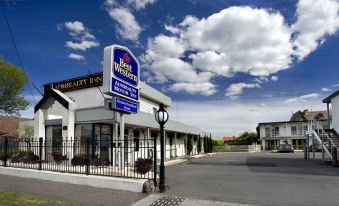 a best western hotel with a blue sign , surrounded by a brick building and a parking lot at Admiralty Inn