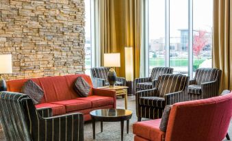 a well - lit hotel lobby with various seating options , including couches and chairs , creating a comfortable and inviting atmosphere at Cambria Hotel Appleton