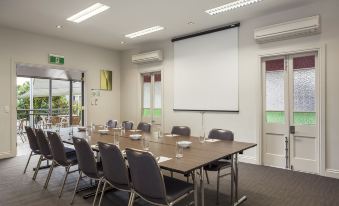 a conference room with a long table , chairs , and a projector screen , ready for a meeting or presentation at Quest Ipswich