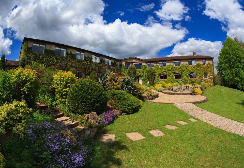 a large house surrounded by a lush green garden , with several benches placed in the area at Best Western Plus Centurion Hotel