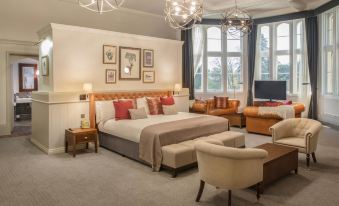 a large bedroom with a king - sized bed , a couch , and several chairs arranged around it at De Vere Tortworth Court