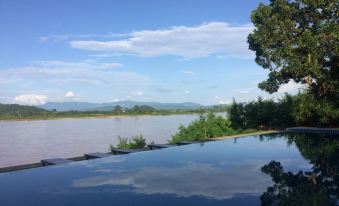 a large pool is situated near a body of water , with mountains in the background at Siam Triangle Hotel