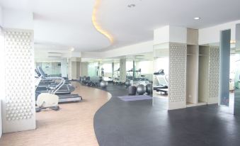 a gym with various exercise equipment , including treadmills and weightlifting machines , arranged in a circular pattern at Hotel Horison Grand Serpong