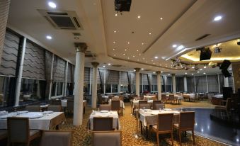 a large , well - lit restaurant with multiple dining tables and chairs arranged for a group of people at Prestige Hotel