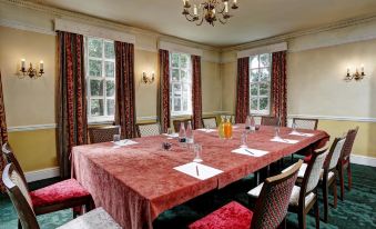 a large conference room with a long table , chairs , and chandeliers , set for a meeting or presentation at The Knaresborough Inn - the Inn Collection Group