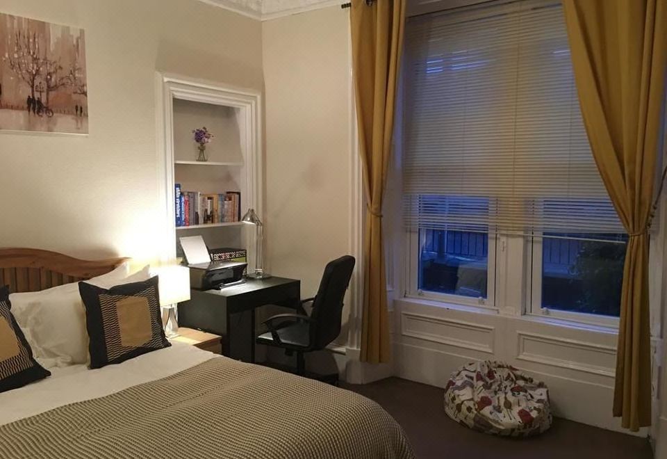 a cozy bedroom with a bed , desk , and window , along with a window seat and a comfortable reading chair at Union Apartments
