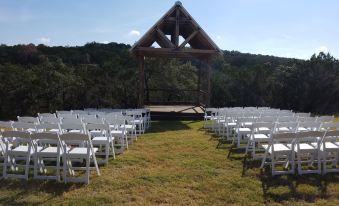 a well - organized outdoor event with white chairs arranged in rows and a wooden structure in the background at Hill Country Casitas