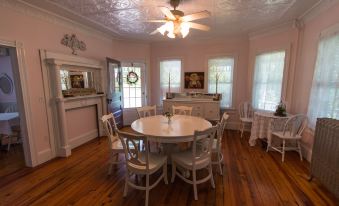 a dining room with a round table surrounded by white chairs , and a ceiling fan hanging from the ceiling at Inn at Tyler Hill