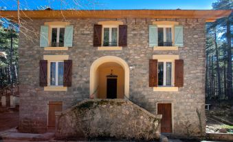 a stone house with a balcony and three windows , situated in a village setting under a clear blue sky at Casa Alta
