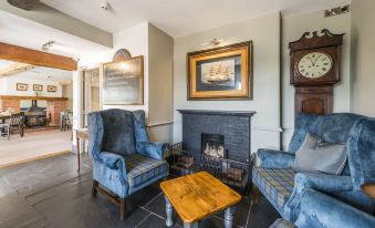 a cozy living room with blue chairs , a fireplace , and a wooden coffee table , surrounded by various decorations at The Rodney