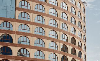 a tall building with a curved design has many windows and a tiled roof on the side at Pullman Zamzam Madina