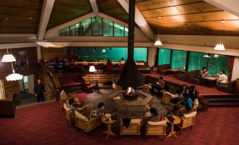 a group of people gathered in a lounge area with large windows and a fireplace at Okushiga Kogen Hotel