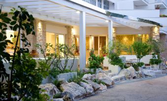 a hotel with a white exterior , featuring a large covered porch and several potted plants at Hotel Orsa Maggiore