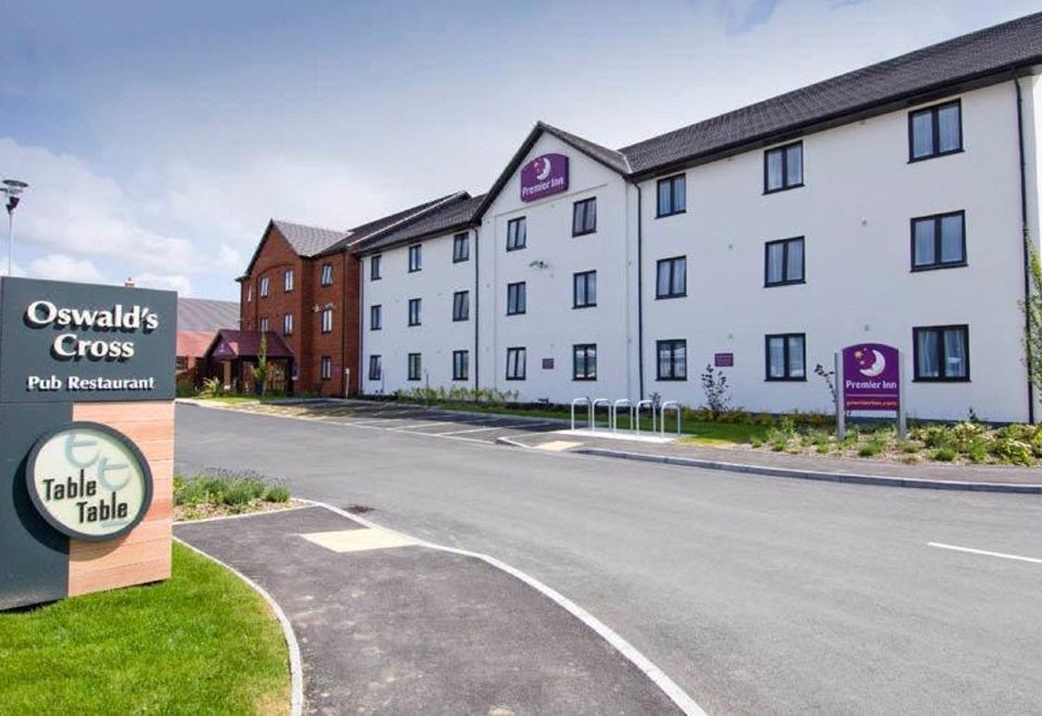 a hotel building with a purple sign on the front , surrounded by a parking lot at Oswestry