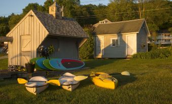 a group of kayaks and canoes are lined up in a yard next to a small house at Lake Bomoseen Lodge