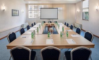 a conference room with a long table , chairs , and a screen , ready for a meeting or presentation at Valamar Meteor Hotel