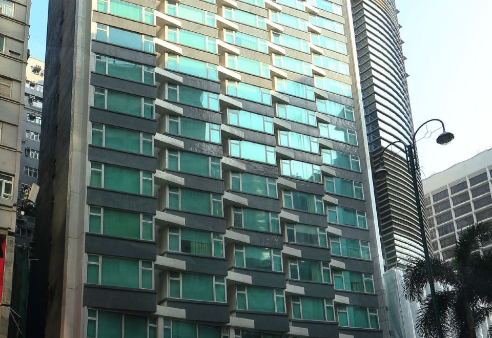 In front of an apartment complex stands a tall building with numerous windows on its side at Imperial Hotel