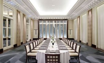 a large , elegant dining room with a long table set for a formal dinner , complete with white tablecloths and elegant chairs at Hotel the Peninsula Paris