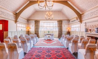 a large room with white chairs and a red rug on the floor , surrounded by chandeliers at Colwall Park - Hotel, Bar & Restaurant