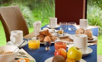 a dining table set with a variety of breakfast items , including pastries , fruit , and coffee at Ibis Styles Paris Mairie de Montreuil
