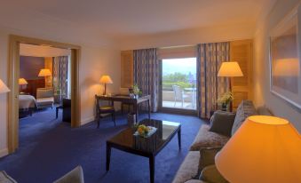 a well - furnished living room with a couch , a dining table , and a balcony overlooking the ocean at Le Royal Hotel - Beirut