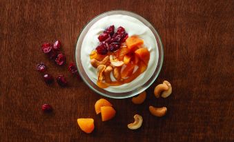 a bowl of yogurt topped with fruit and nuts , placed on a wooden table surrounded by dried fruit at SpringHill Suites Alexandria