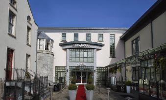 a modern building with a red carpet leading up to the entrance , surrounded by trees at Oriel House Hotel