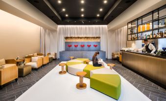 a woman is sitting on a colorful couch in a modern room with white walls and wooden furniture at Glam Milano