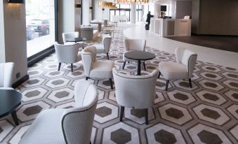 a modern , minimalist lounge area with white chairs and tables arranged in a hexagonal pattern on a geometric patterned carpet at Hotel Bahía