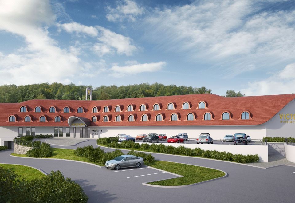 a large red brick building with multiple stories and a parking lot in front of it at Hotel Victory