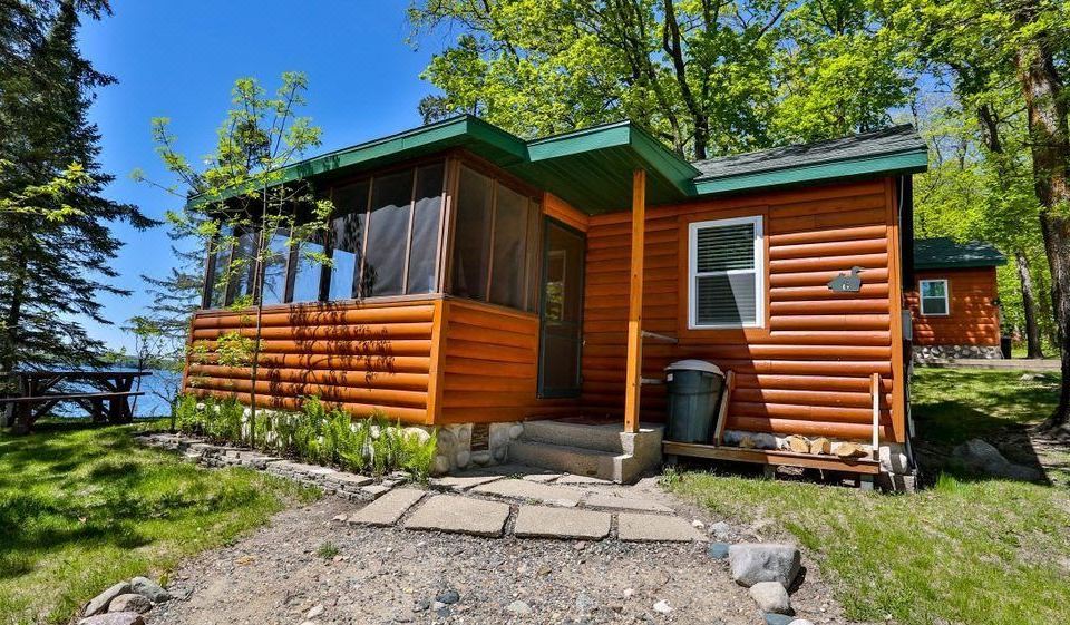 a small wooden cabin surrounded by trees , with a dirt road leading up to it at Kohl's Resort