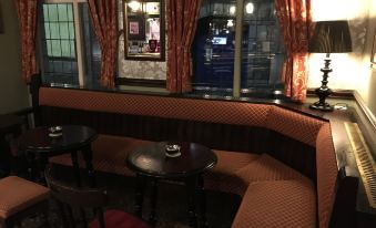 a cozy restaurant with wooden tables and chairs , red carpeted floor , and large windows at The Bulls Head