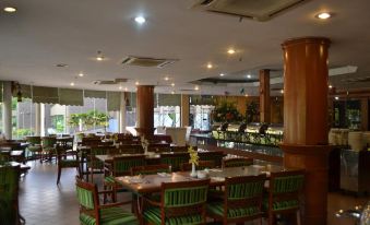 a large , well - lit restaurant with multiple dining tables and chairs , as well as a bar area at De Rhu Beach Resort