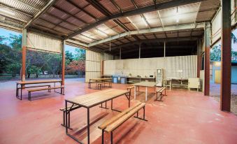 an empty outdoor area with wooden benches , a table , and a kitchen under a metal roof at Breeze Holiday Parks - Mary River