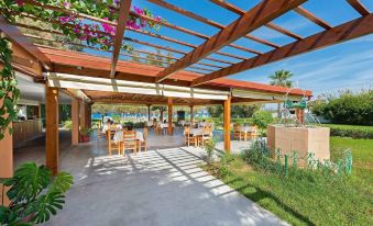 a large wooden pergola with a bar and several tables surrounding it , creating a cozy outdoor dining area at Bayside Hotel Katsaras