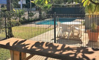a backyard with a pool surrounded by a fence , a dining table , and several chairs at Balonne River Motor Inn
