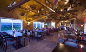 a large , open dining area with wooden tables and chairs , a long banquet table , and a bar in the background at Hlid Fisherman's Village