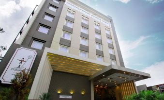 a modern hotel building with a white facade and a glass entrance , under a blue sky with clouds at Pranaya Boutique Hotel